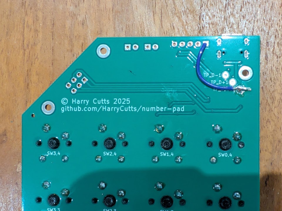 Photo of the top part of the TwentyPad PCB, with a wire added to link the TP_VBUS test point with the VCC pin of the (unpopulated) expansion header.